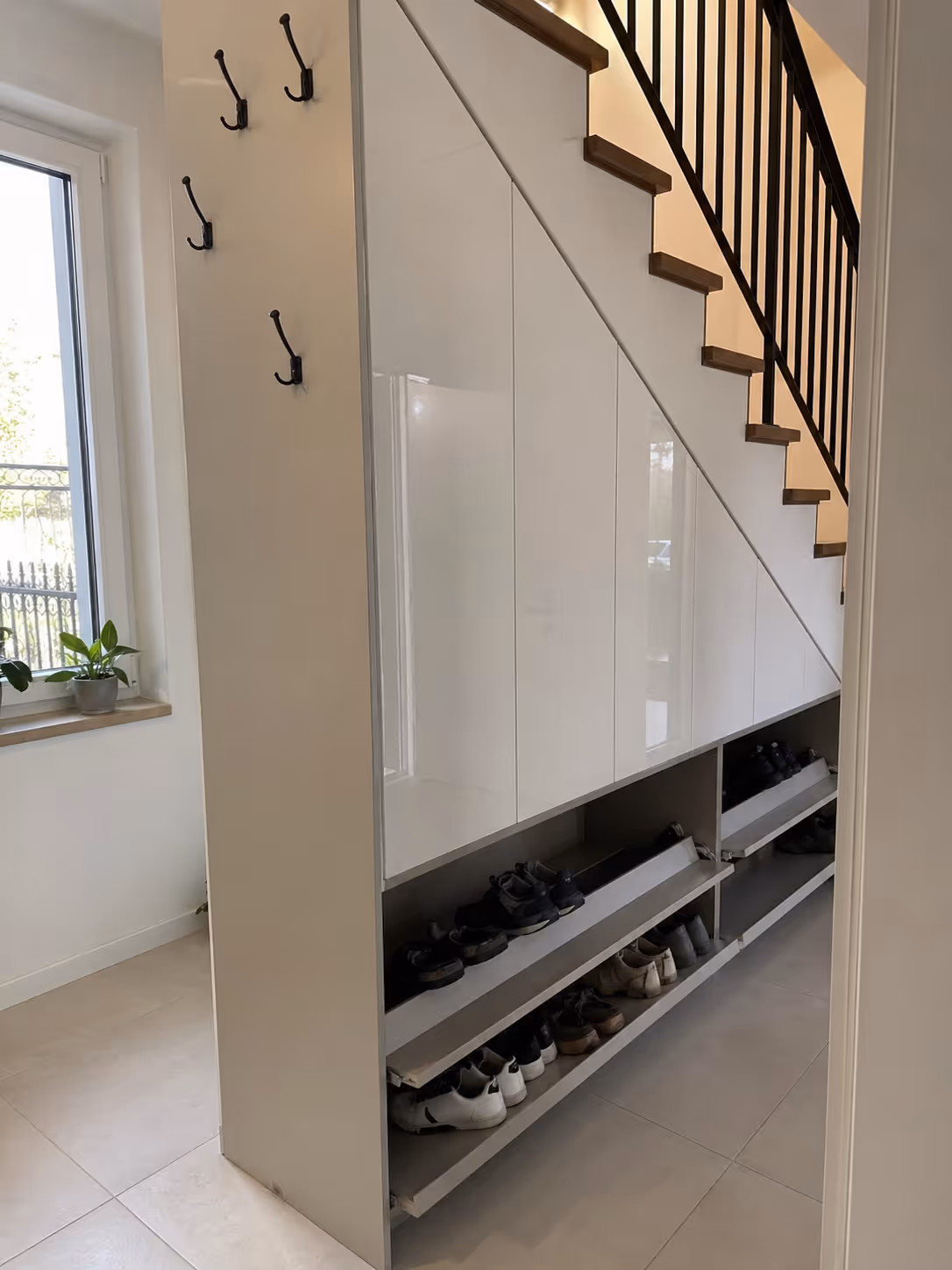 Schowek pod schodami na buty na wymiar Wrocław — wyciągane półki obuwnicze, biały laminat