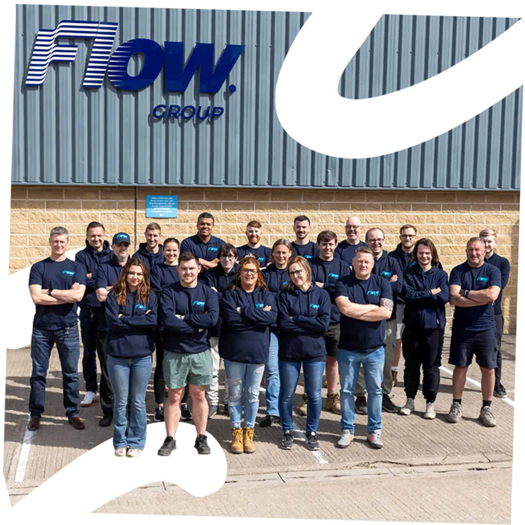 Group of 20 Flow Group staff in company apparel standing in front of building with logo.