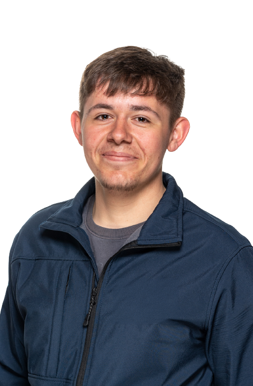 Young man with short brown hair wearing a navy blue zip-up jacket over a gray shirt, smiling slightly at the camera.
