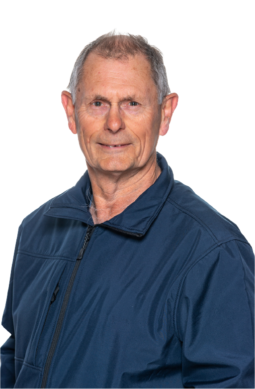 Portrait of an elderly man with short gray hair wearing a navy blue zip-up jacket, smiling slightly against a transparent background.