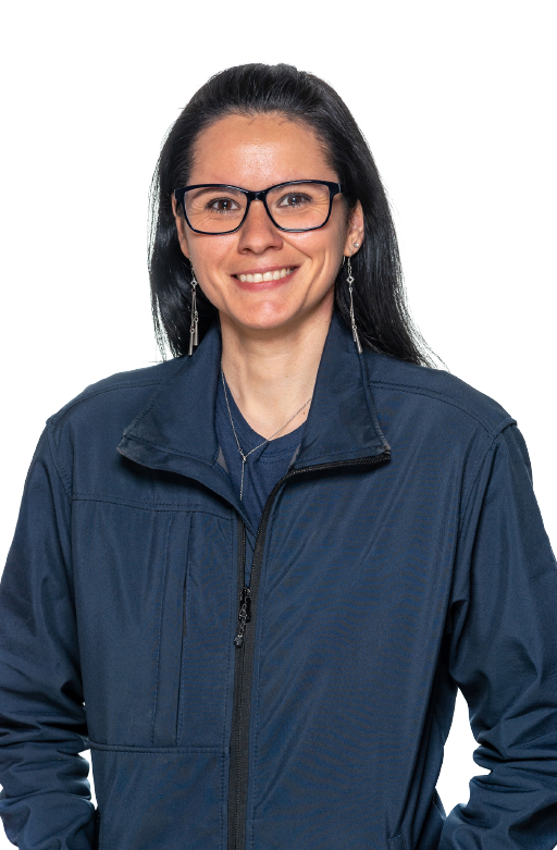 Smiling woman with long black hair wearing black rectangular glasses, dangling earrings, a necklace, and a dark blue zip-up jacket.