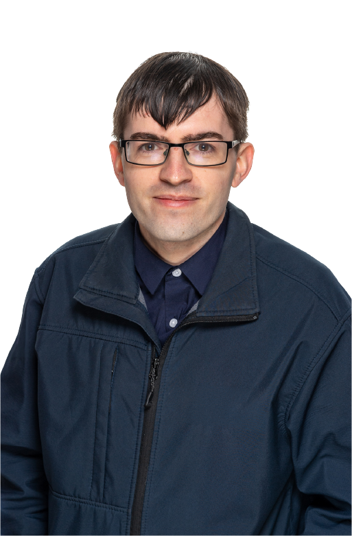 A young man with short dark hair and glasses, wearing a navy blue jacket over a dark button-up shirt, smiling slightly at the camera.