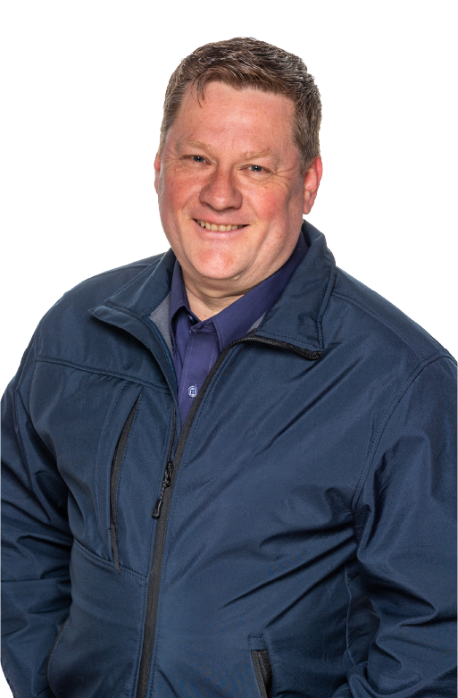 Smiling middle-aged man with short light brown hair wearing a navy blue zip-up jacket over a blue collared shirt, standing against a white background.