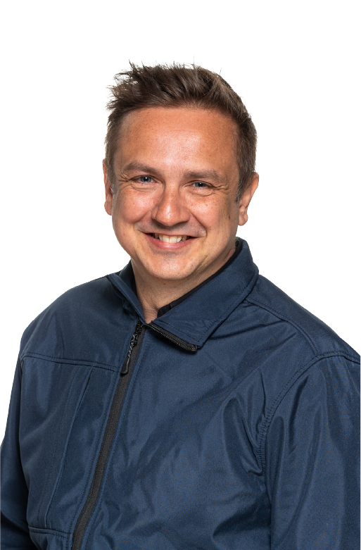 Smiling man with short light brown hair wearing a dark blue zip-up jacket, posing against a transparent background.