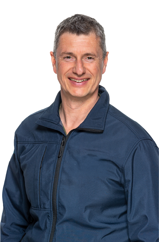Smiling middle-aged man with short gray hair wearing a navy blue zip-up jacket.