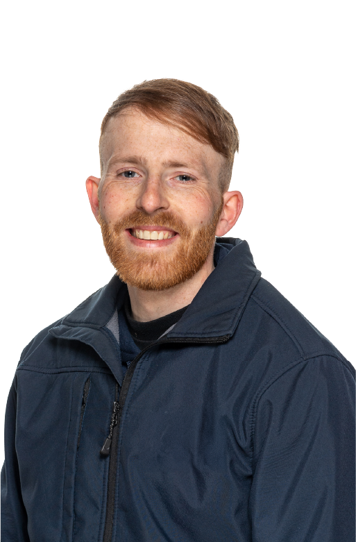 Smiling white man with short light brown hair and a red beard wearing a dark blue zip-up jacket over a black shirt, facing forward.