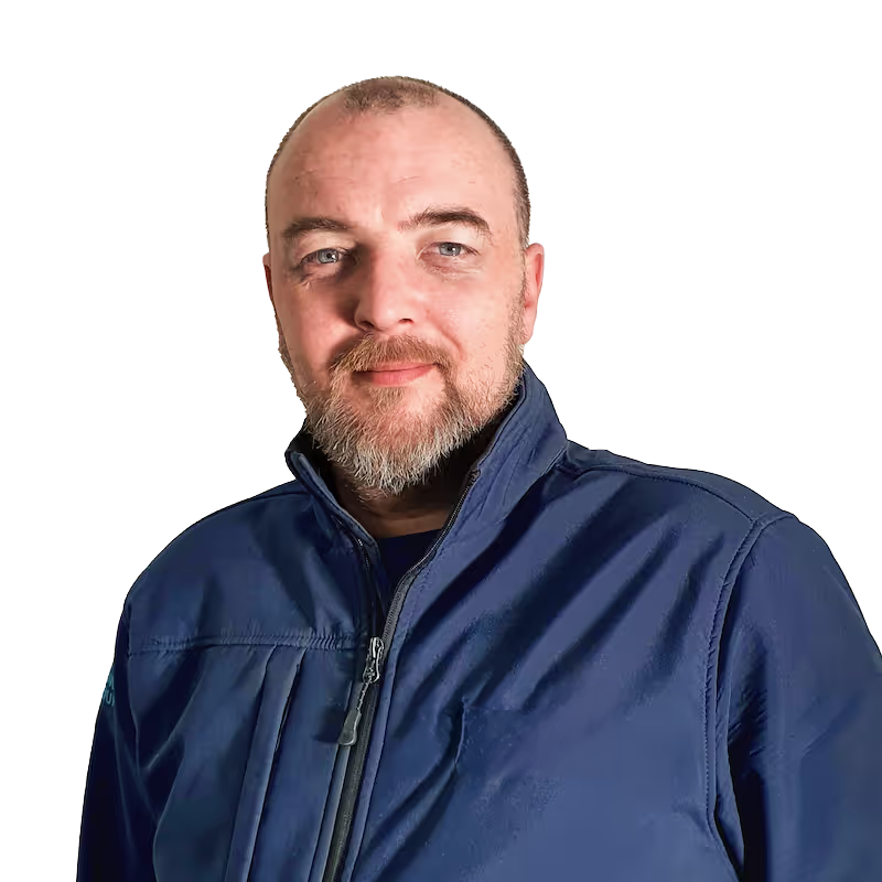 Portrait of a middle-aged man with a short beard and short hair wearing a dark blue jacket against a white background.