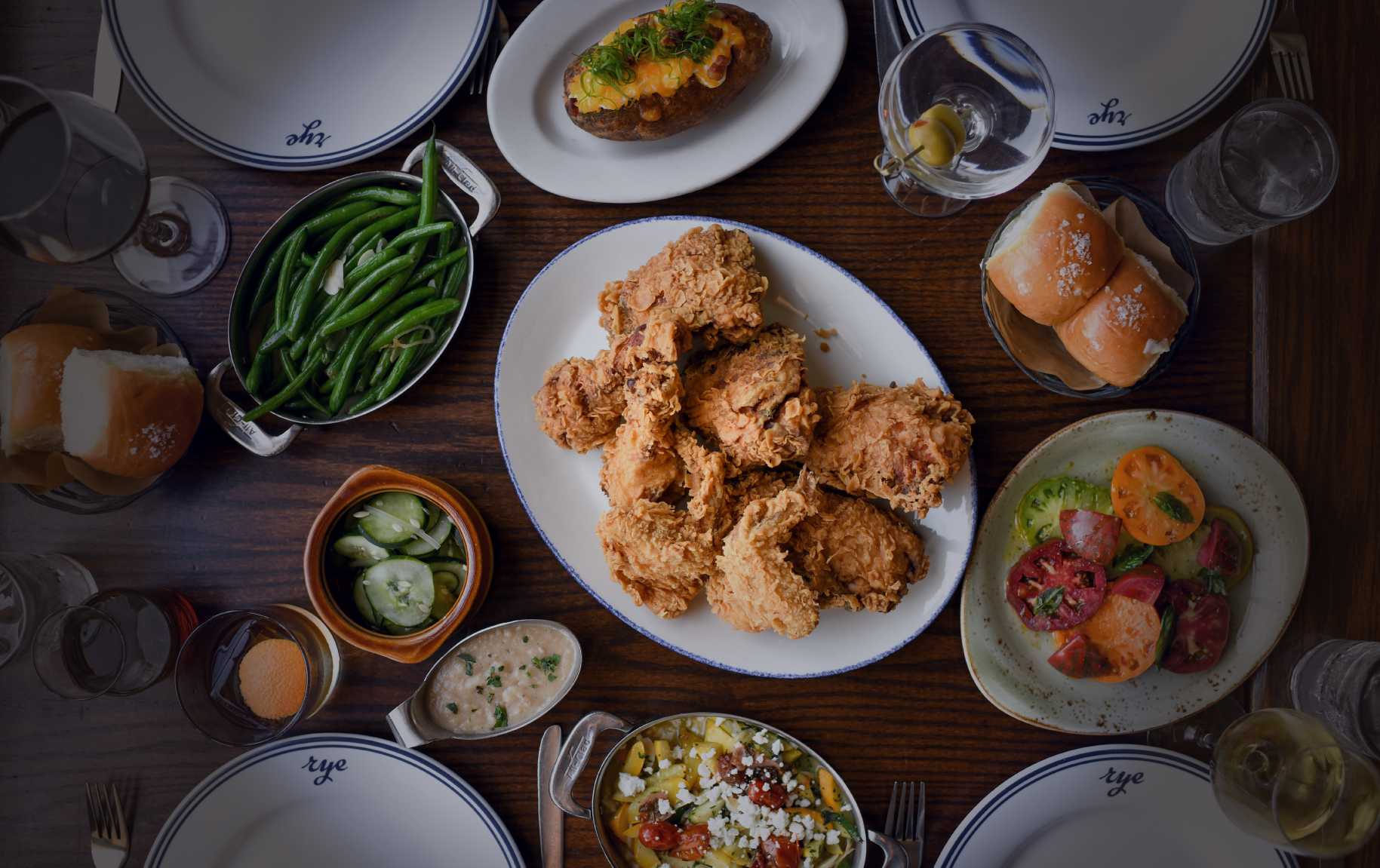 A table full of food with a plate of chicken and green beans.