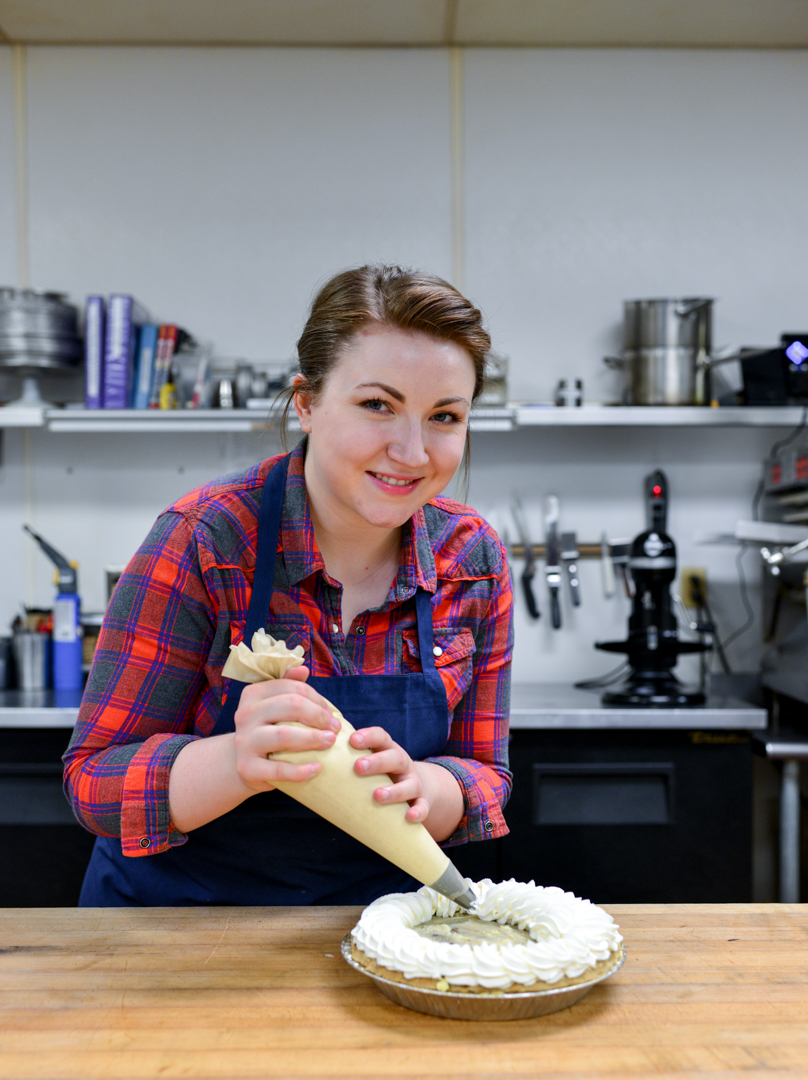 A woman is making a pie in a kitchen.