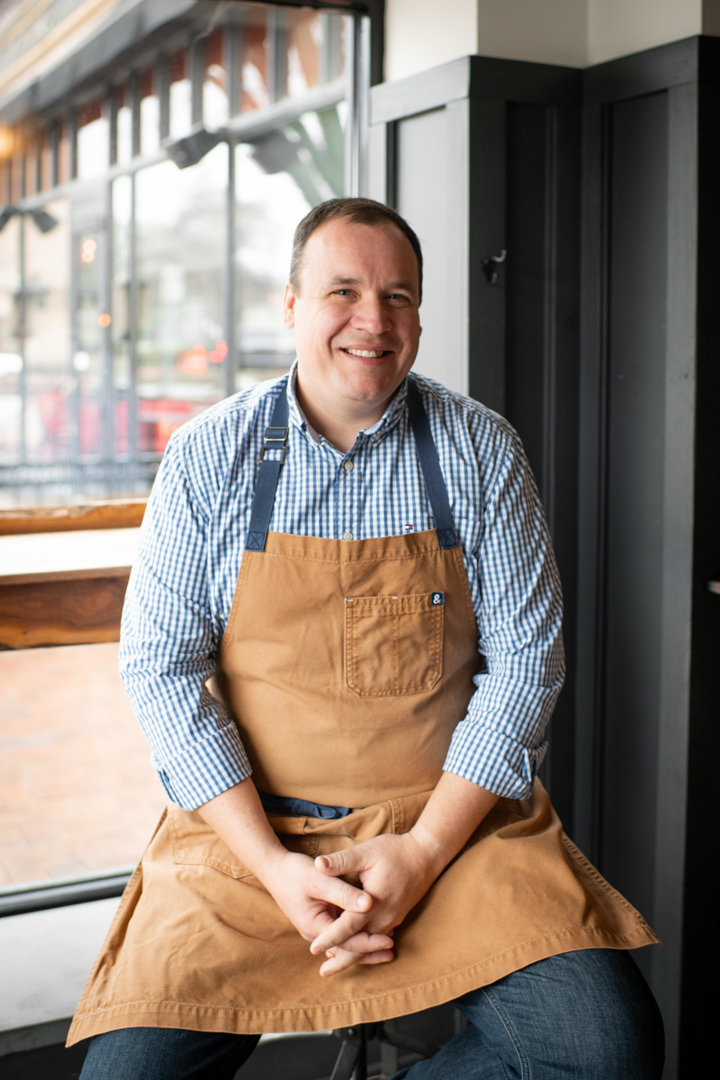 A man wearing an apron and smiling.