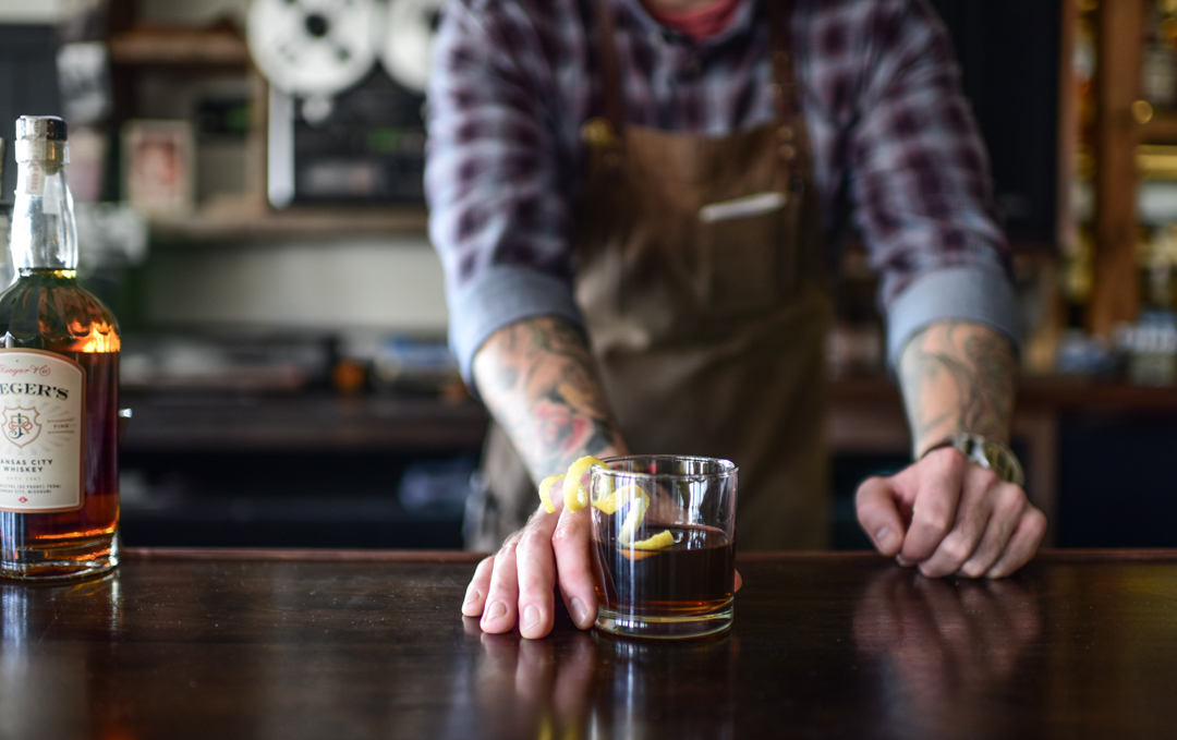 A man with a tattooed arm holding a glass of lemonade.