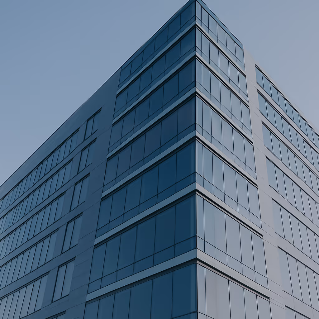 Ecke eines modernen Bürogebäudes mit blauen Glasfenstern vor klarem Himmel.