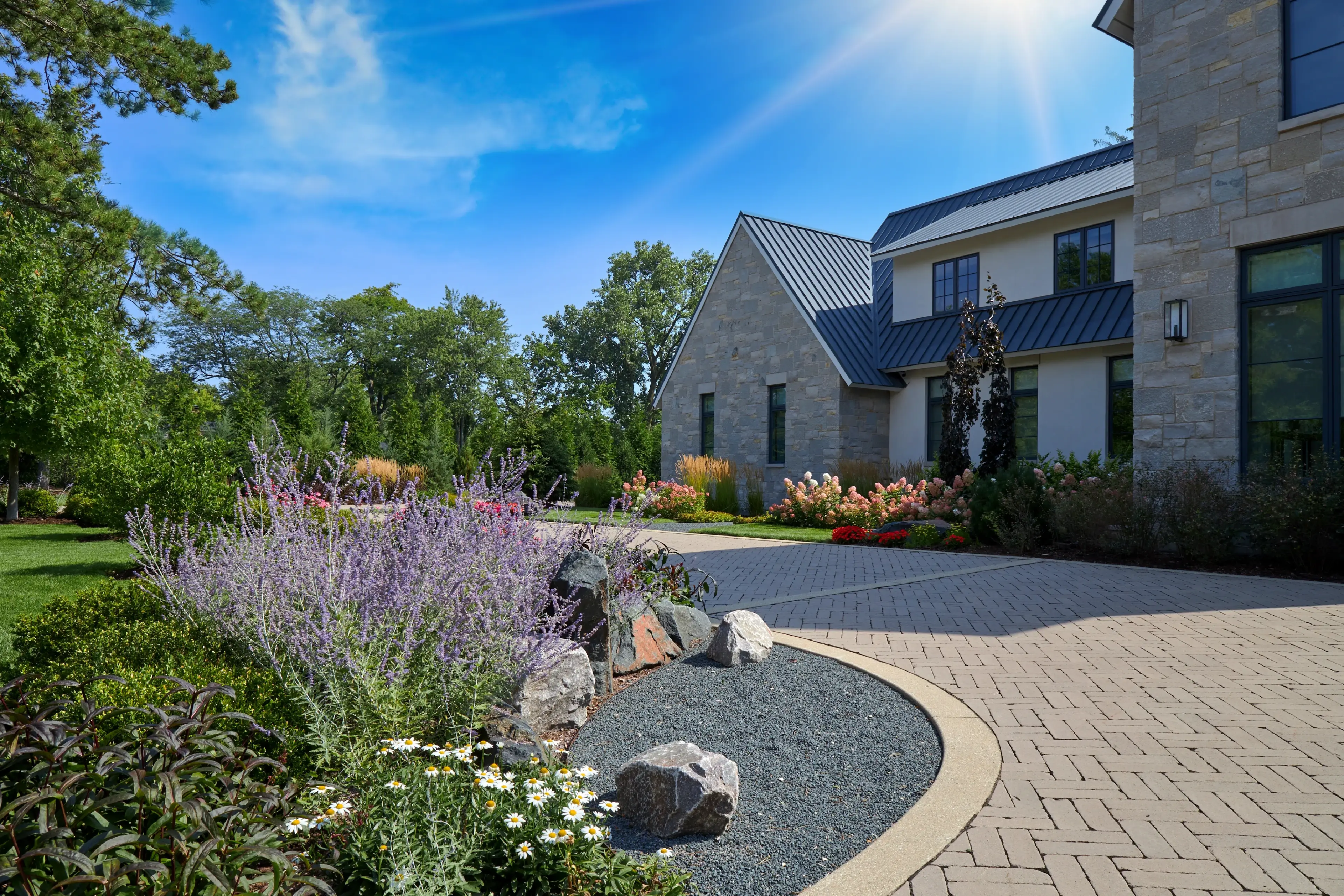 Stone designed driveway wrapping in front of stone house