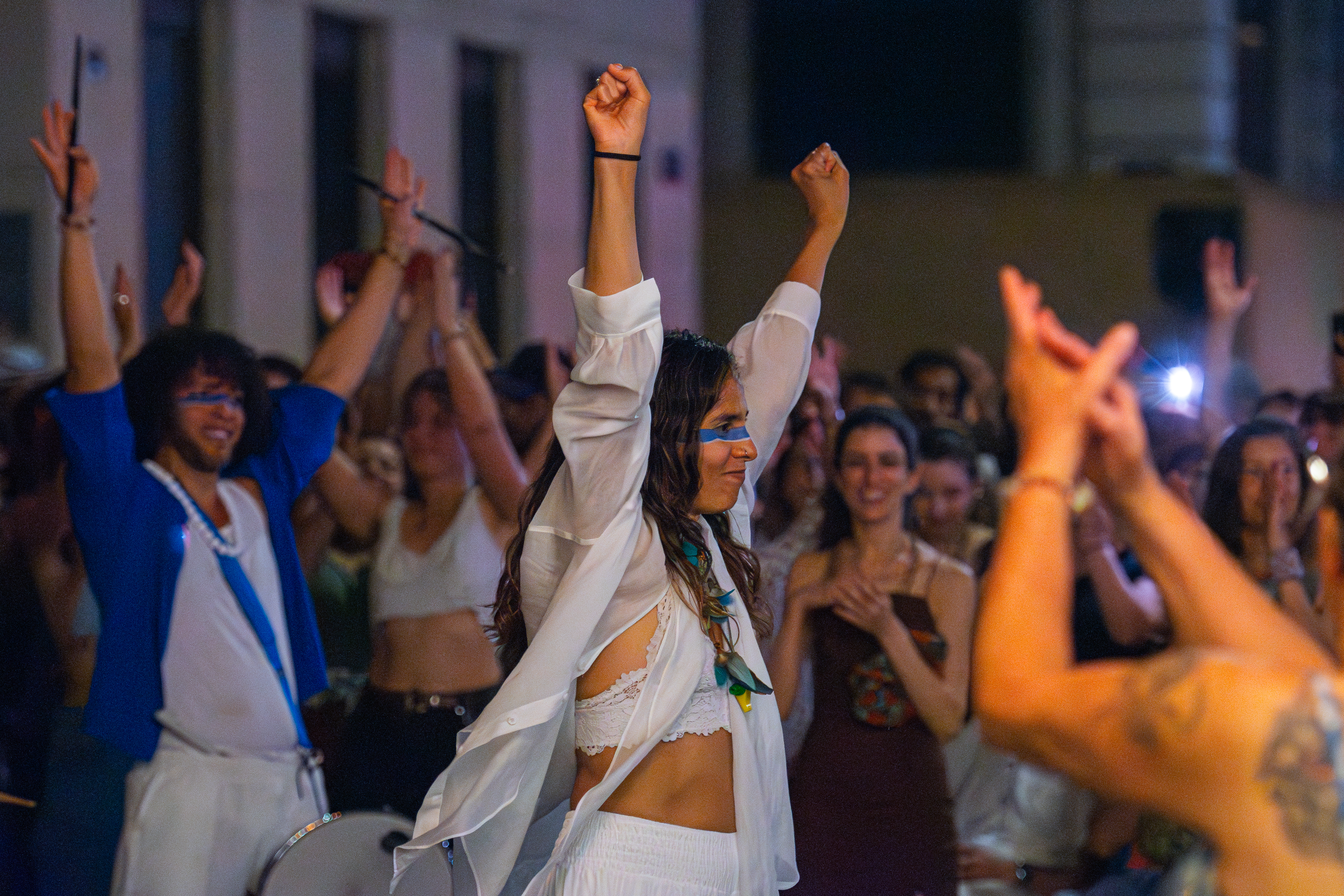 Crowd dancing outdoors at night with arms raised at music festival