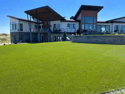 Modern luxury home with large green lawn and clear blue sky in the background.