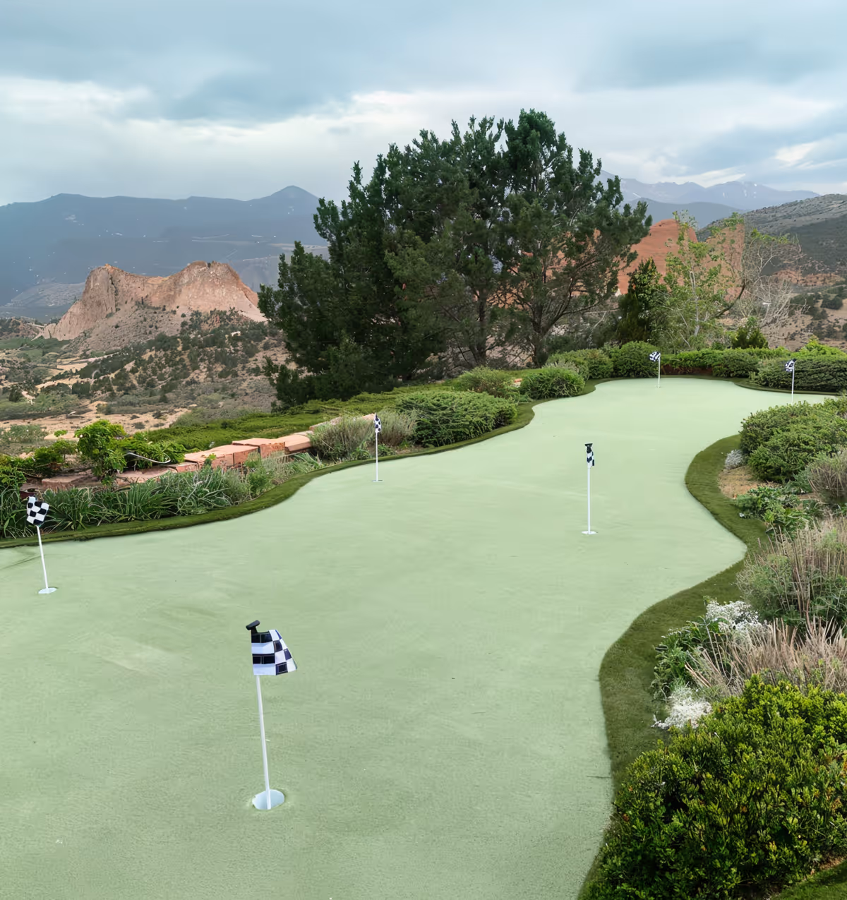 A modern house with a large backyard featuring an artificial putting green and golf hole.
