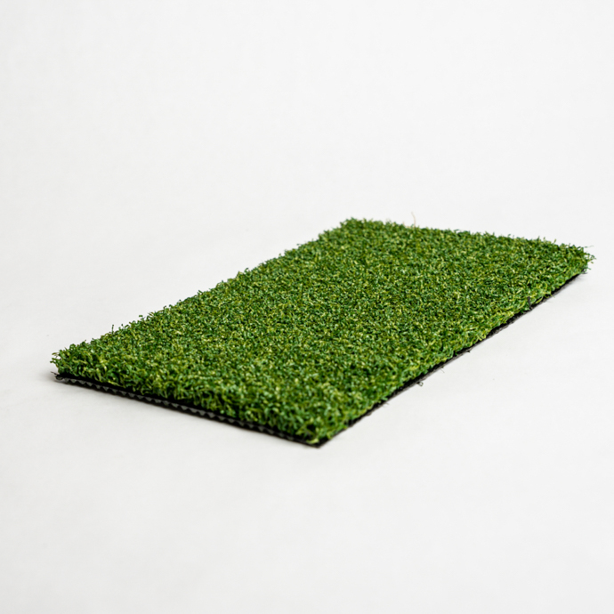 Rectangular sample of artificial turf with green and brown strands on a white background.
