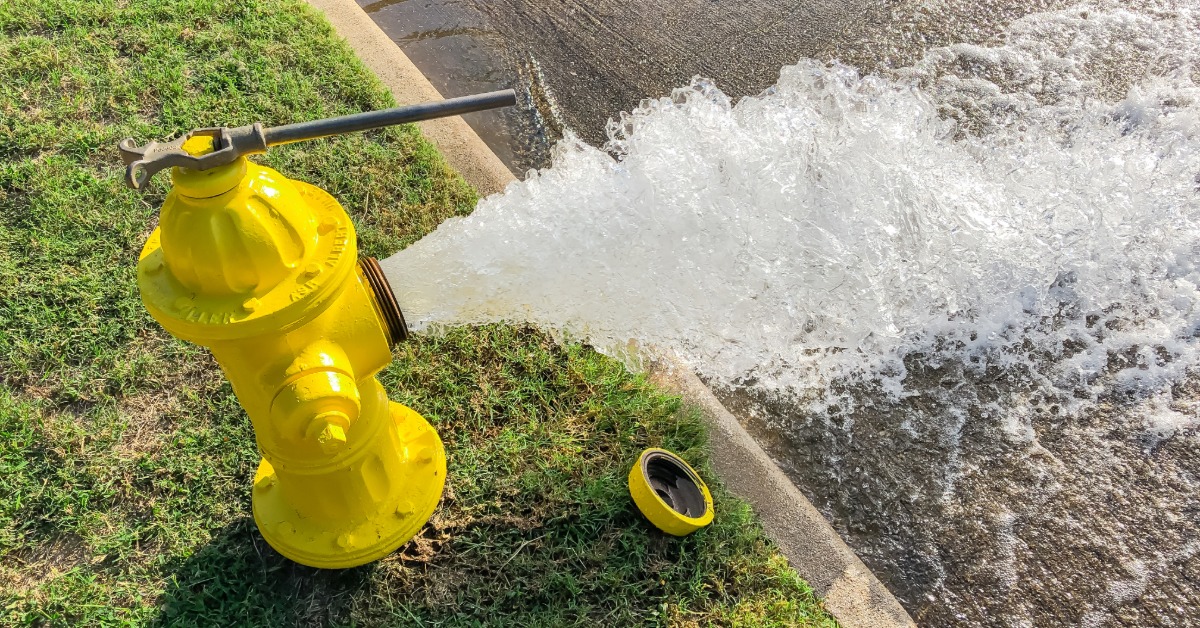 A yellow fire hydrant releasing water. 