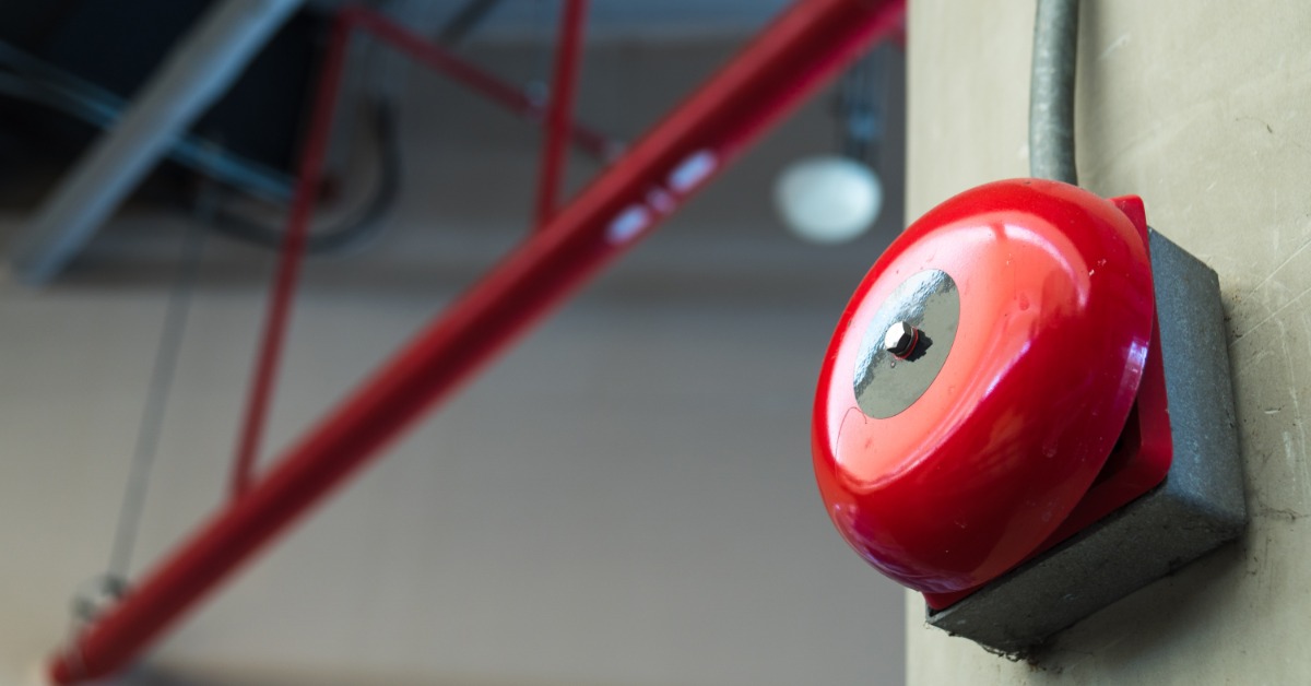 A red circular fire alarm on the wall. 