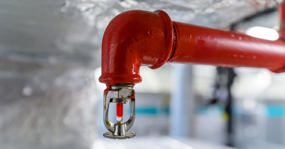 A red fire sprinkler pointing towards the floor.