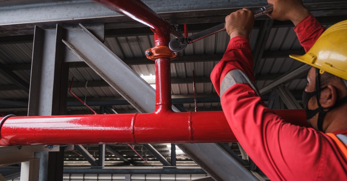 A worker working on a fire sprinkler pipe. 