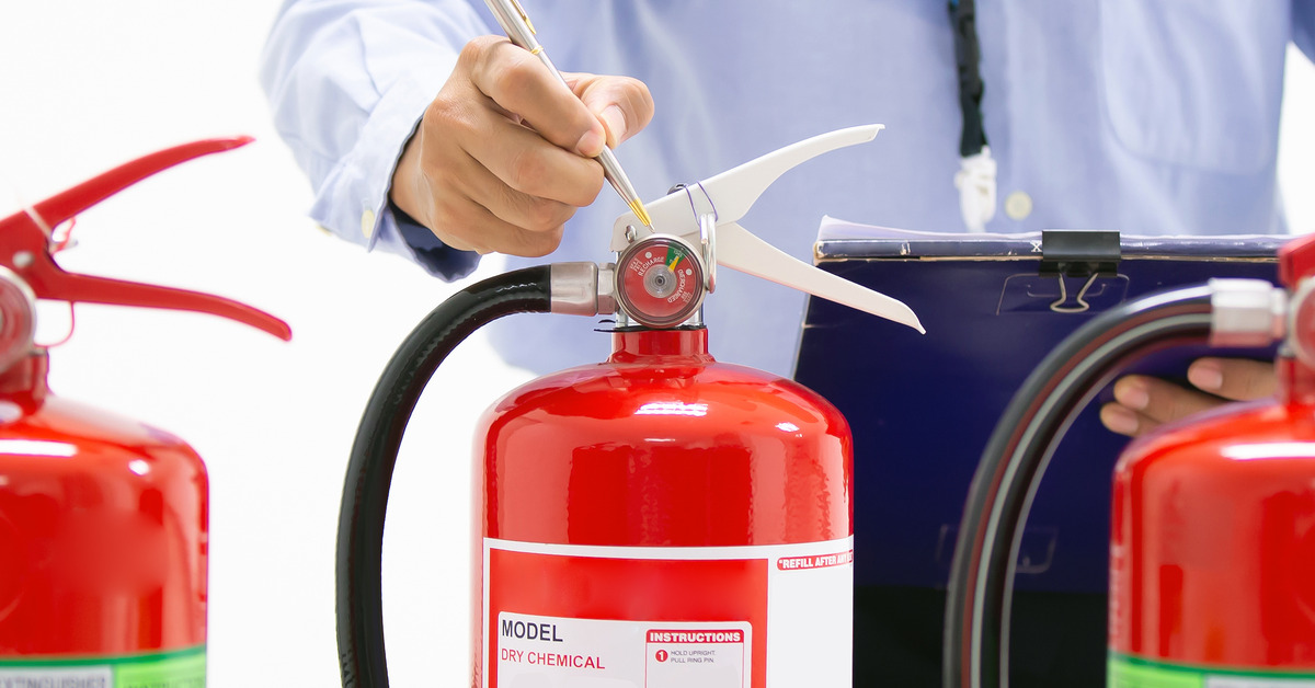 A person inspecting three different fire extinguishers. 