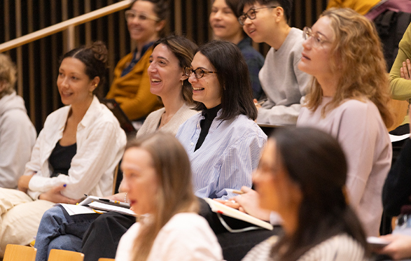 Group of diverse women seated and engaged, smiling during a lecture or presentation.