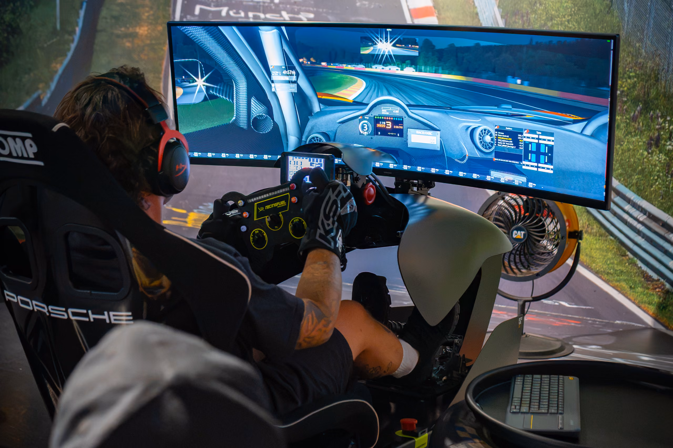 Fahrer mit rotem Headset sitzt im Porsche-Rennsimulator vor gebogenem Breitbildschirm