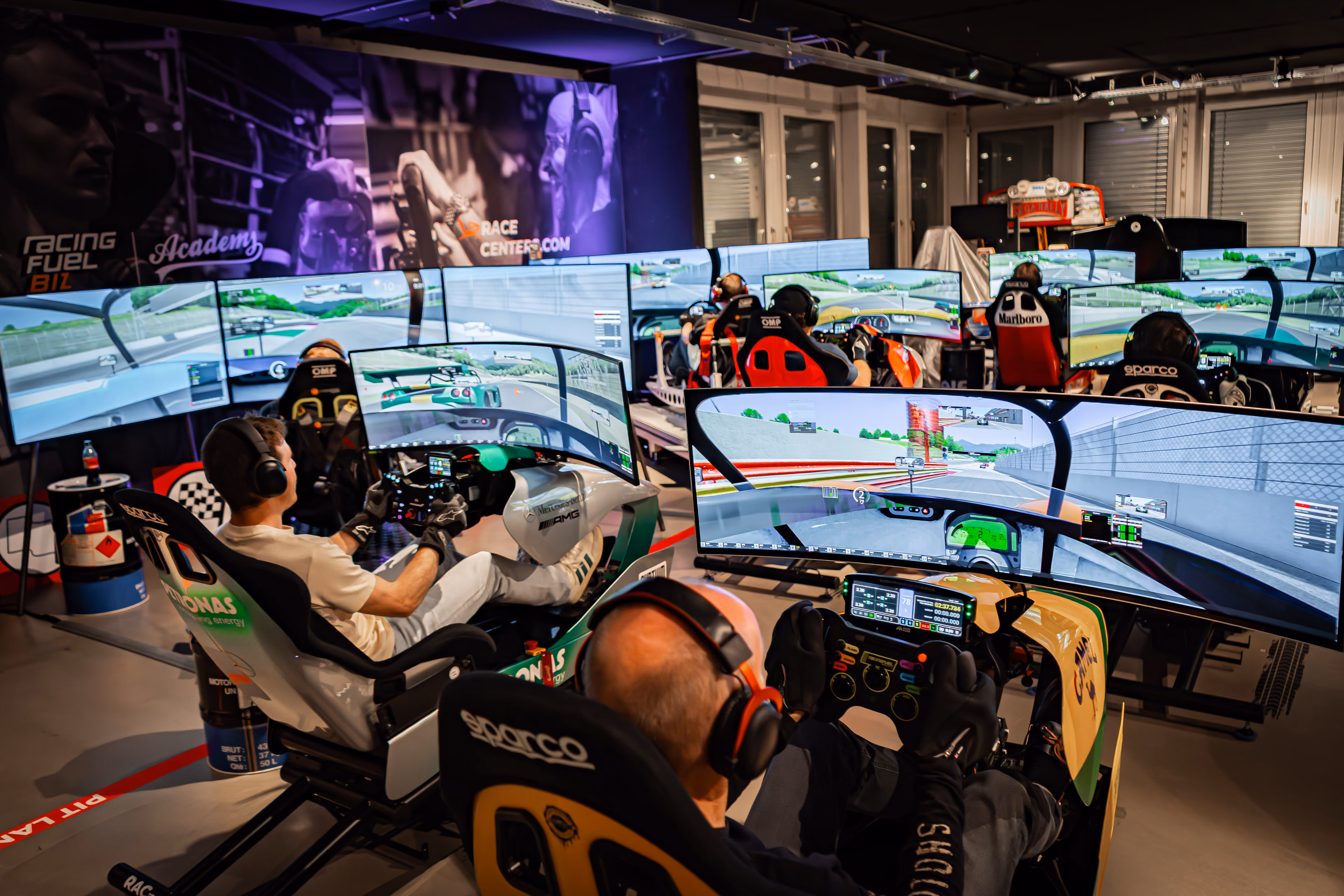 Übersicht mehrerer Rennsimulatoren mit Fahrern im RacingFuel Academy Center
