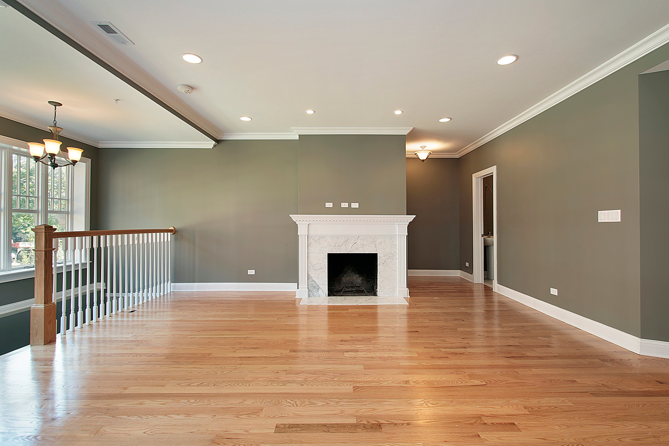 Empty living room with freshly refinished hardwood and a white fireplace by Brazil Floors