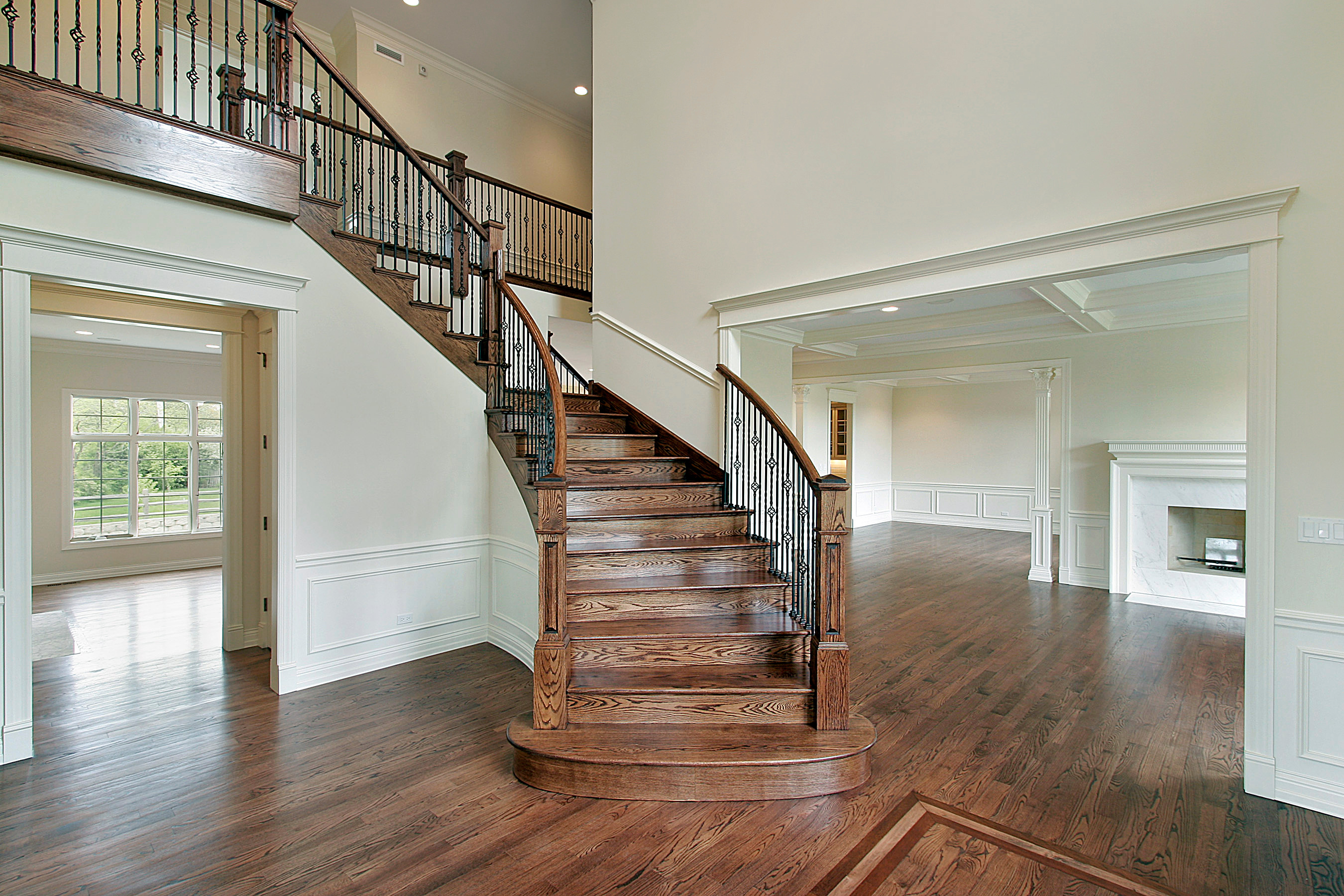 Refinished hardwood and a stained staircase in a bright entry by Brazil Floors