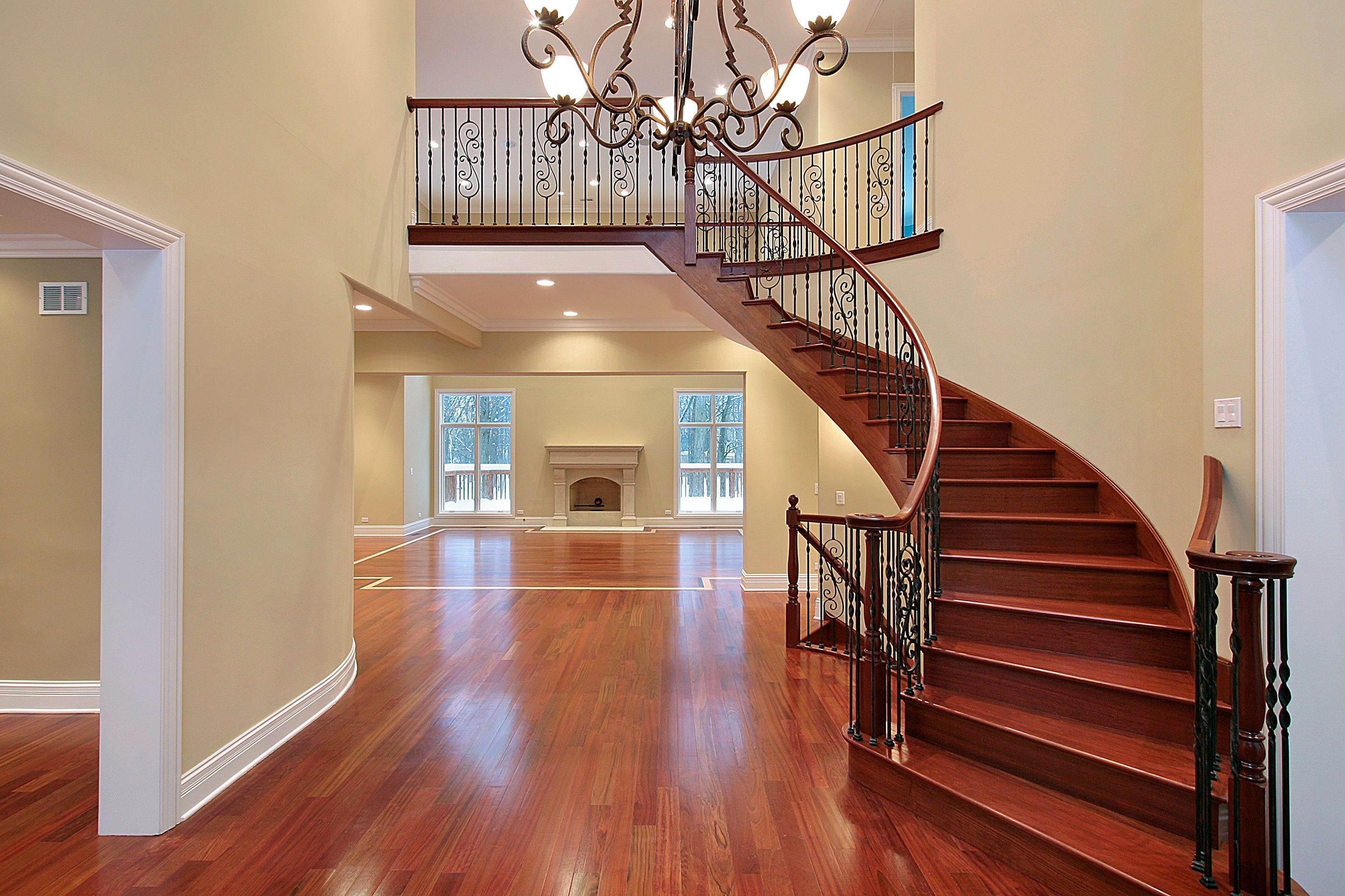 Refinished hardwood floor at the foot of a curved staircase by Brazil Floors