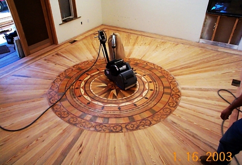 Buffer working around a wood medallion during a refinish by Brazil Floors