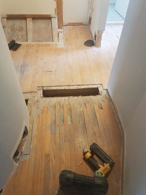 Damaged boards cut out and new wood going in during a floor repair by Brazil Floors