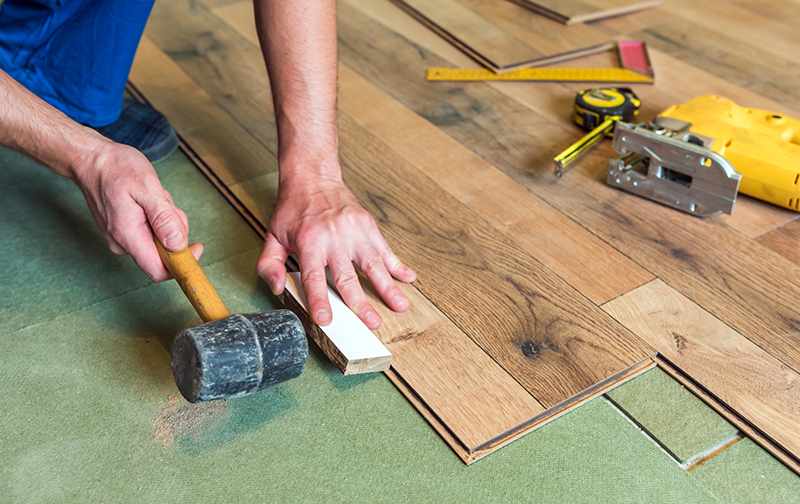 Installer tapping a vinyl plank into place with a mallet for Brazil Floors