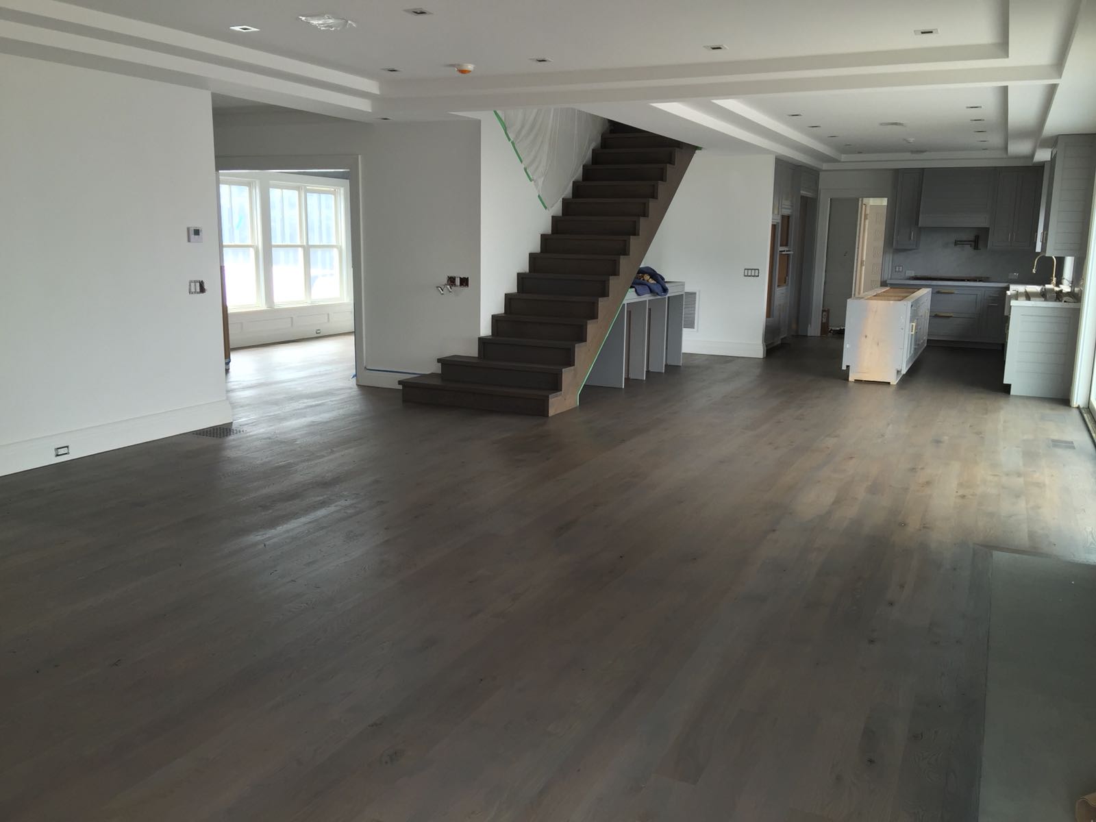 Open floor plan with a gray stained hardwood refinish by Brazil Floors