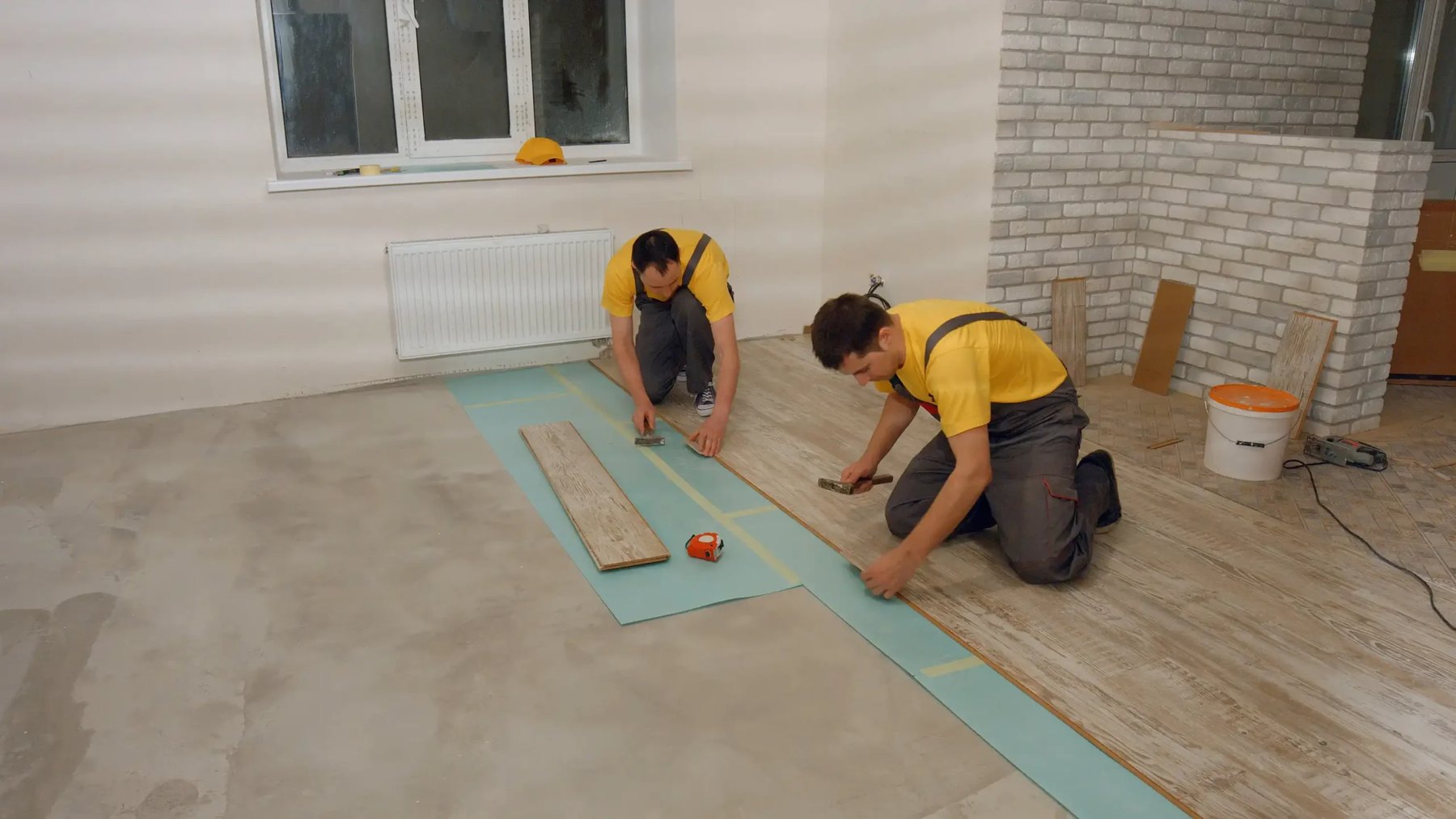 Crew setting vinyl plank rows over underlayment, Brazil Floors