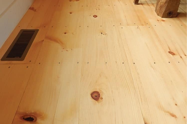 Knotty eastern white pine plank floor with wide boards and a floor vent, laid by Brazil Floors
