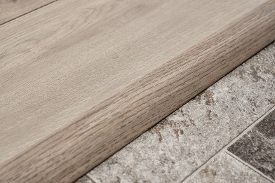 Light oak laminate reducer ramping down to a stone tile floor, Brazil Floors