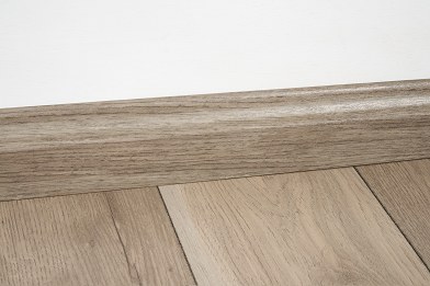 Laminate wall base in light oak running along a white wall, Brazil Floors