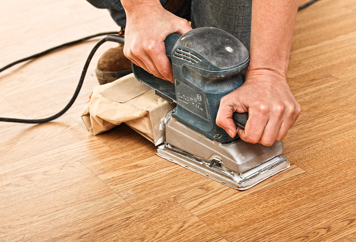 Hand sanding a hardwood board before refinishing in Warwick, RI