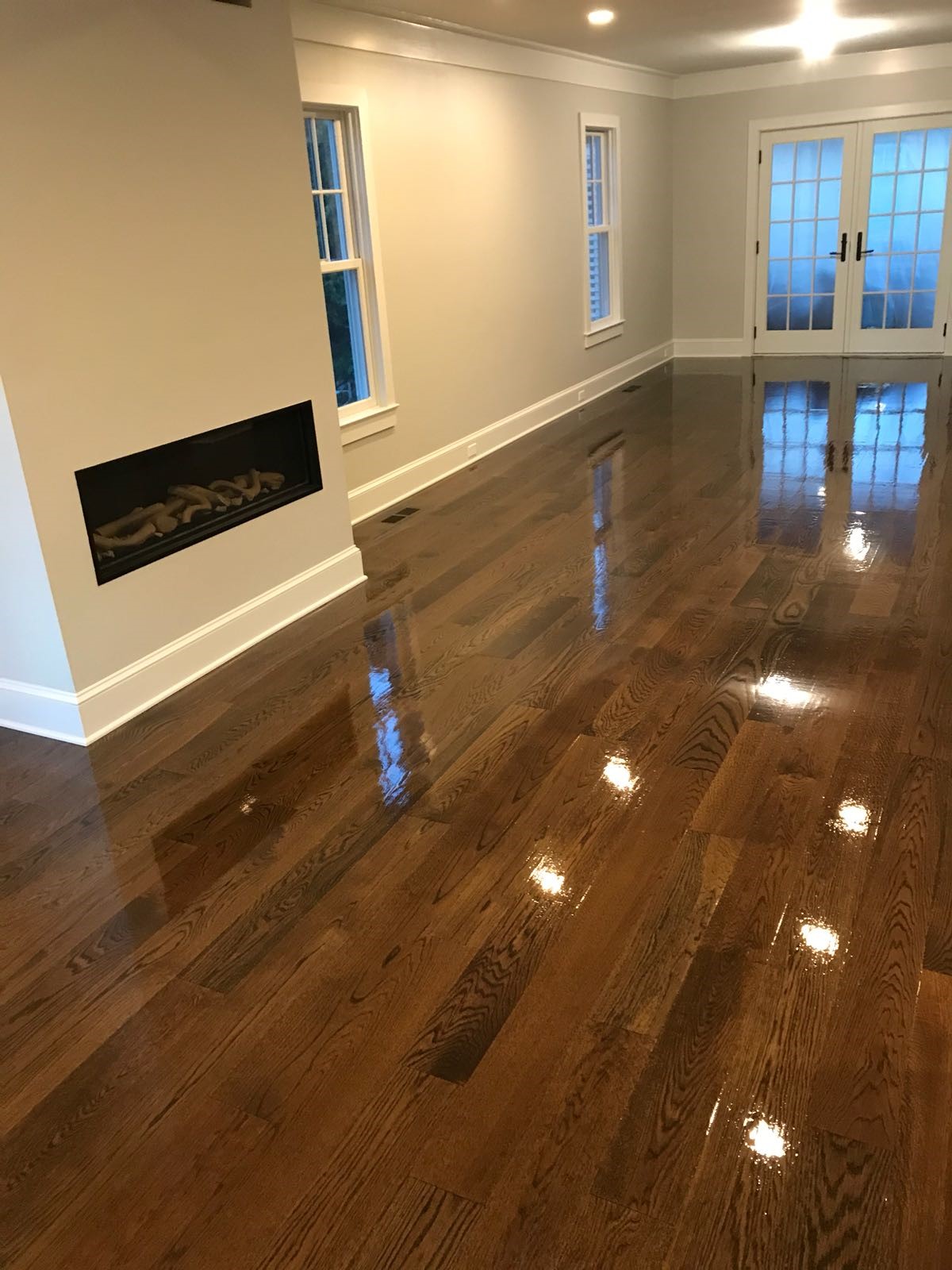 High-gloss hardwood floor beside a modern fireplace, floor refinishing in Johnston, RI