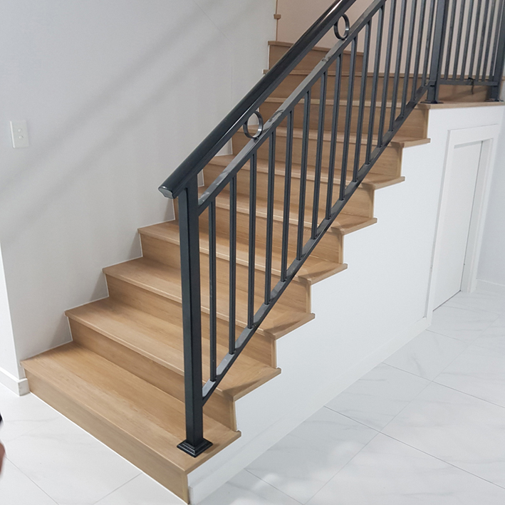 Oak stair treads with white risers and a black metal railing