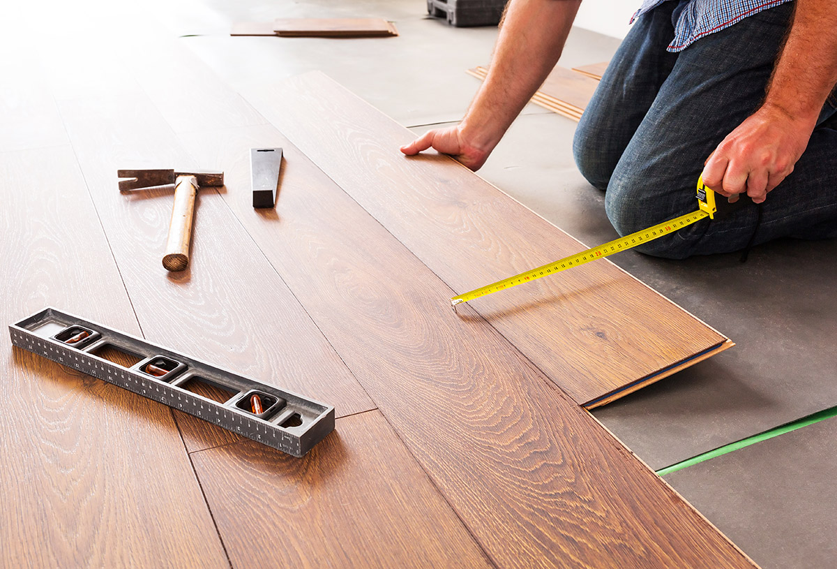 Installer measuring luxury vinyl plank during installation
