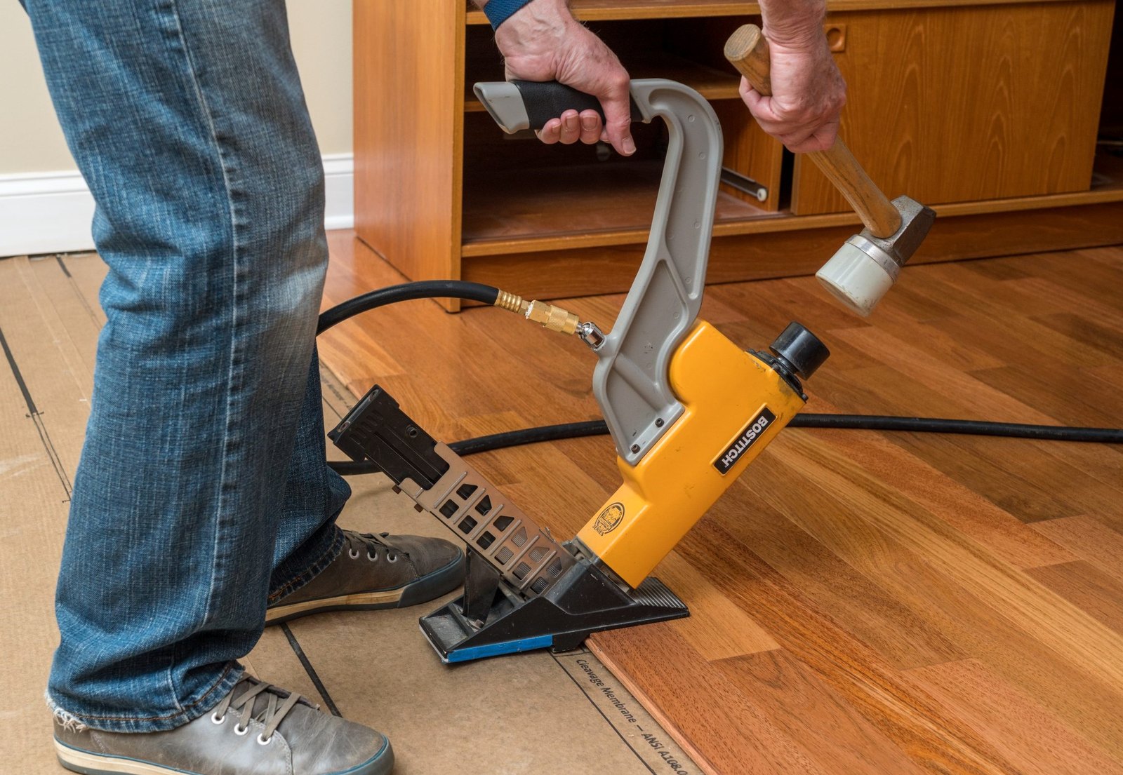 Close view of an installer using a flooring nailer in Johnston, Brazil Floors
