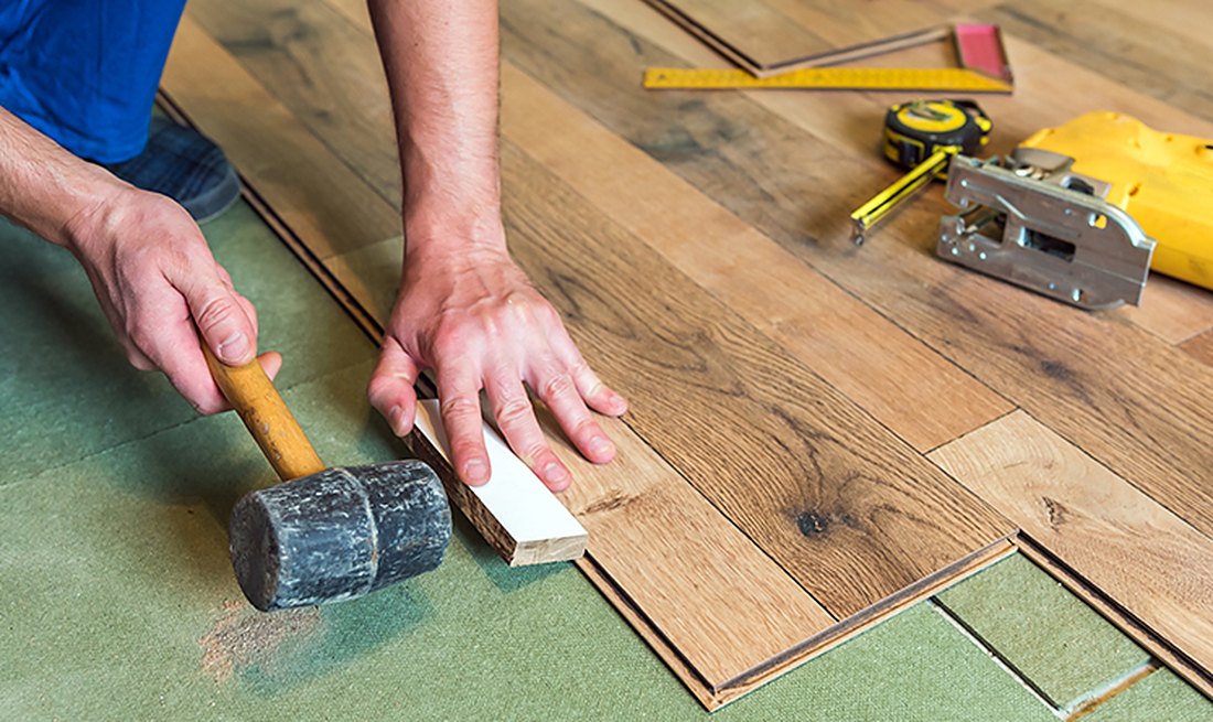 Installer tapping a plank over green underlayment in Anthony, Brazil Floors