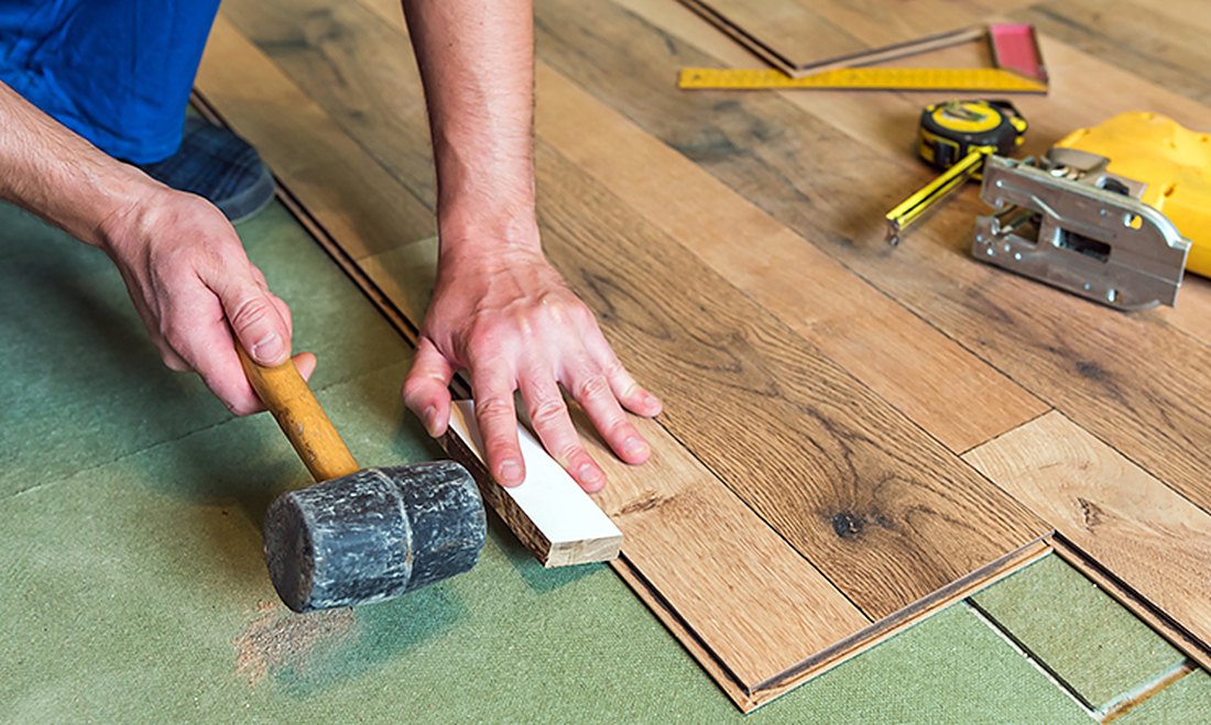 Mallet tapping a vinyl row over underlayment in Ashton, Brazil Floors