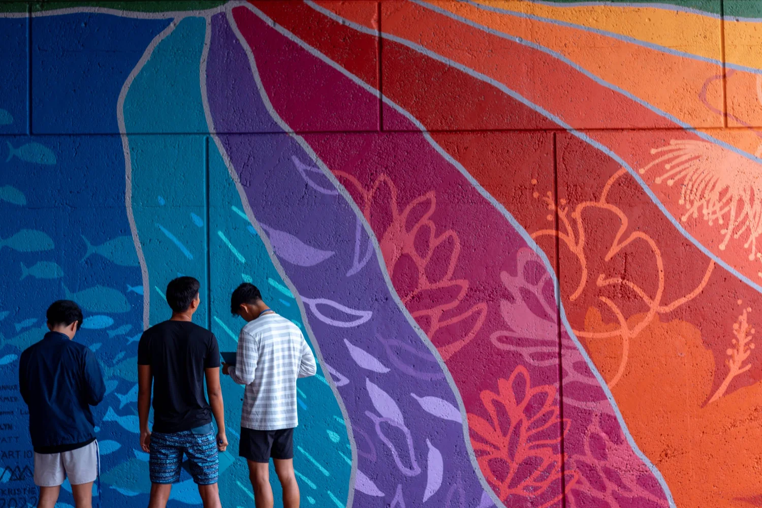 Students standing in front of a decorative mural
