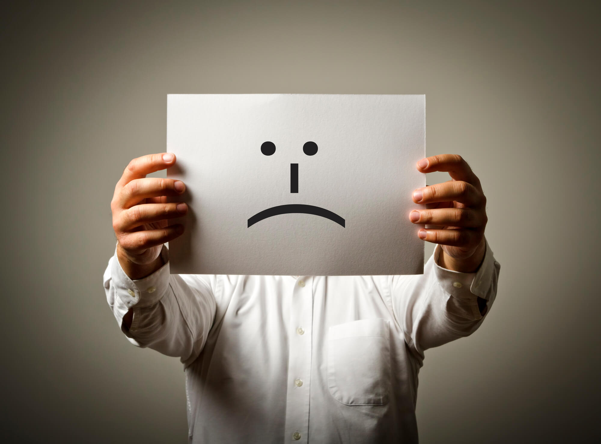 businessman holding paper with sad face drawing