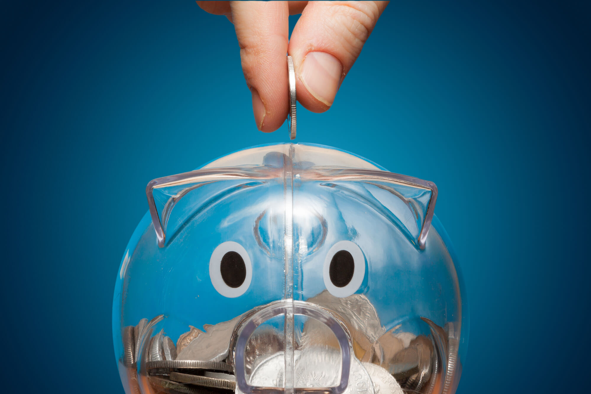 Person putting a coin in a piggy bank
